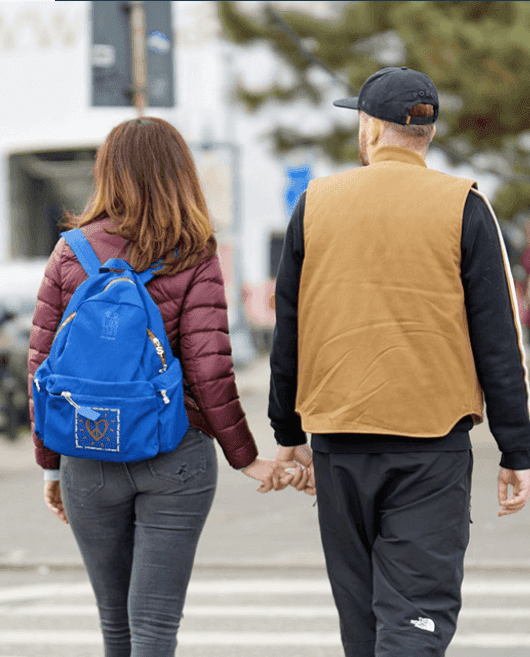 A man and woman holding hands while walking down the street.